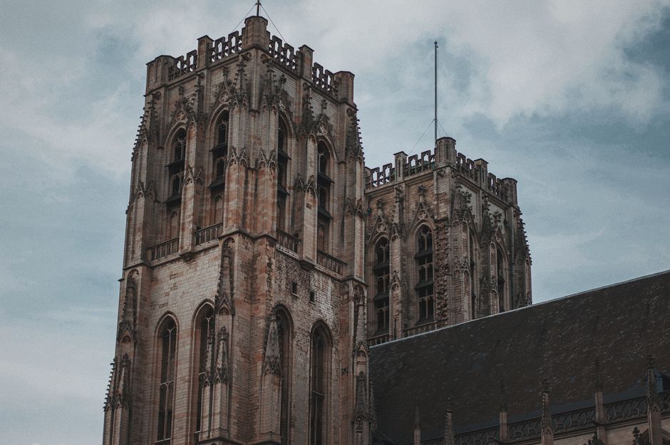 Low angle view of a majestic Gothic cathedral tower showcasing intricate architectural details against a cloudy sky.