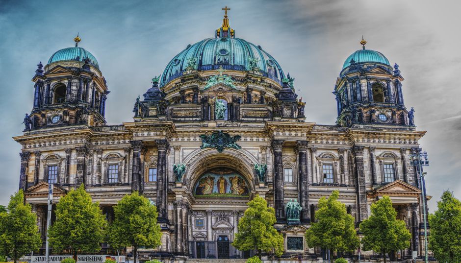 A dramatic view of Berlin Cathedral's historic architecture against a moody sky.